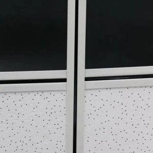Close-up view of an office cubicle divider featuring a black and white design with a perforated panel.