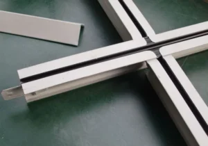 Close-up of a suspended ceiling grid system with intersecting white metal T-bars on a dark surface.