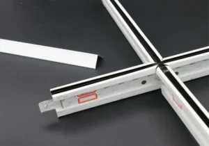 Components of a suspended ceiling grid system including metal strips and connectors on a black surface.