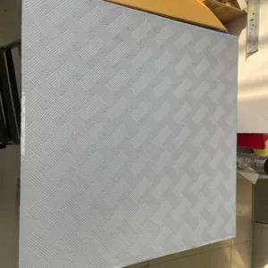 Textured ceiling panel featuring a raised geometric pattern with a basket weave design, placed on a table.