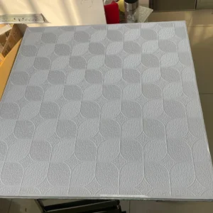 Textured tile surface featuring geometric patterns reflecting light in a bright room setting.