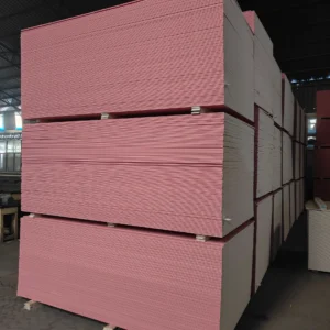 Rows of pink and white drywall panels stacked in a warehouse setting, ready for distribution or use in construction projects.